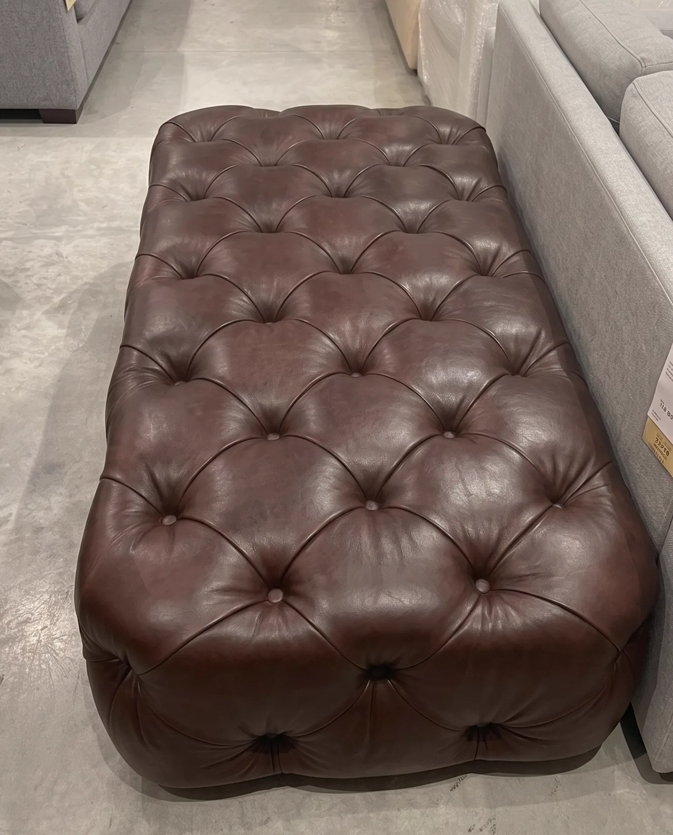 Dark-brown deep-buttoned leather ottoman after patina restoration